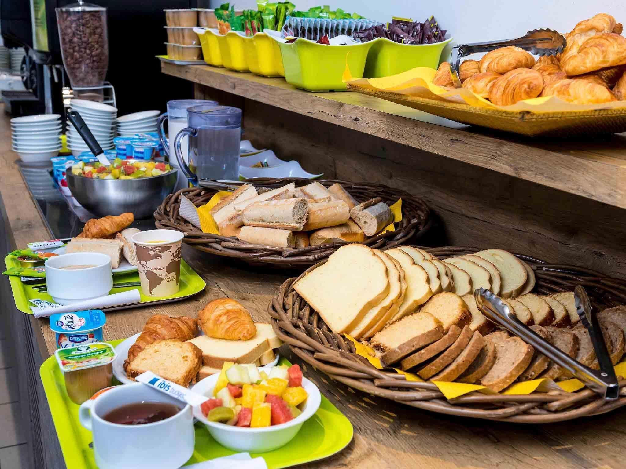 Un buffet proposant une variété d’aliments, notamment du pain, des pâtisseries, des fruits et des boissons.