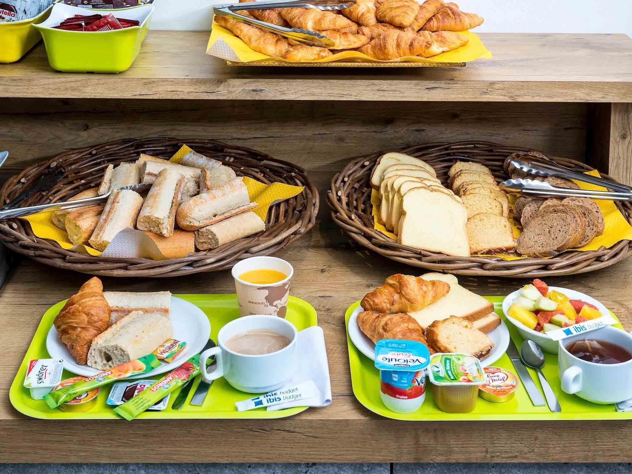 Een ontbijtbuffet met verschillende soorten brood, gebak en drankjes.