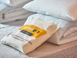 Una cama bien tendida con una almohada y un edredón doblado.