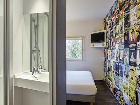 A bathroom with a shower, sink, and a wall decorated with travel posters.