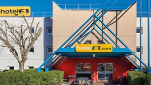 A modern hotel with a prominent yellow sign reading "hotelf1.com" and a red entrance.