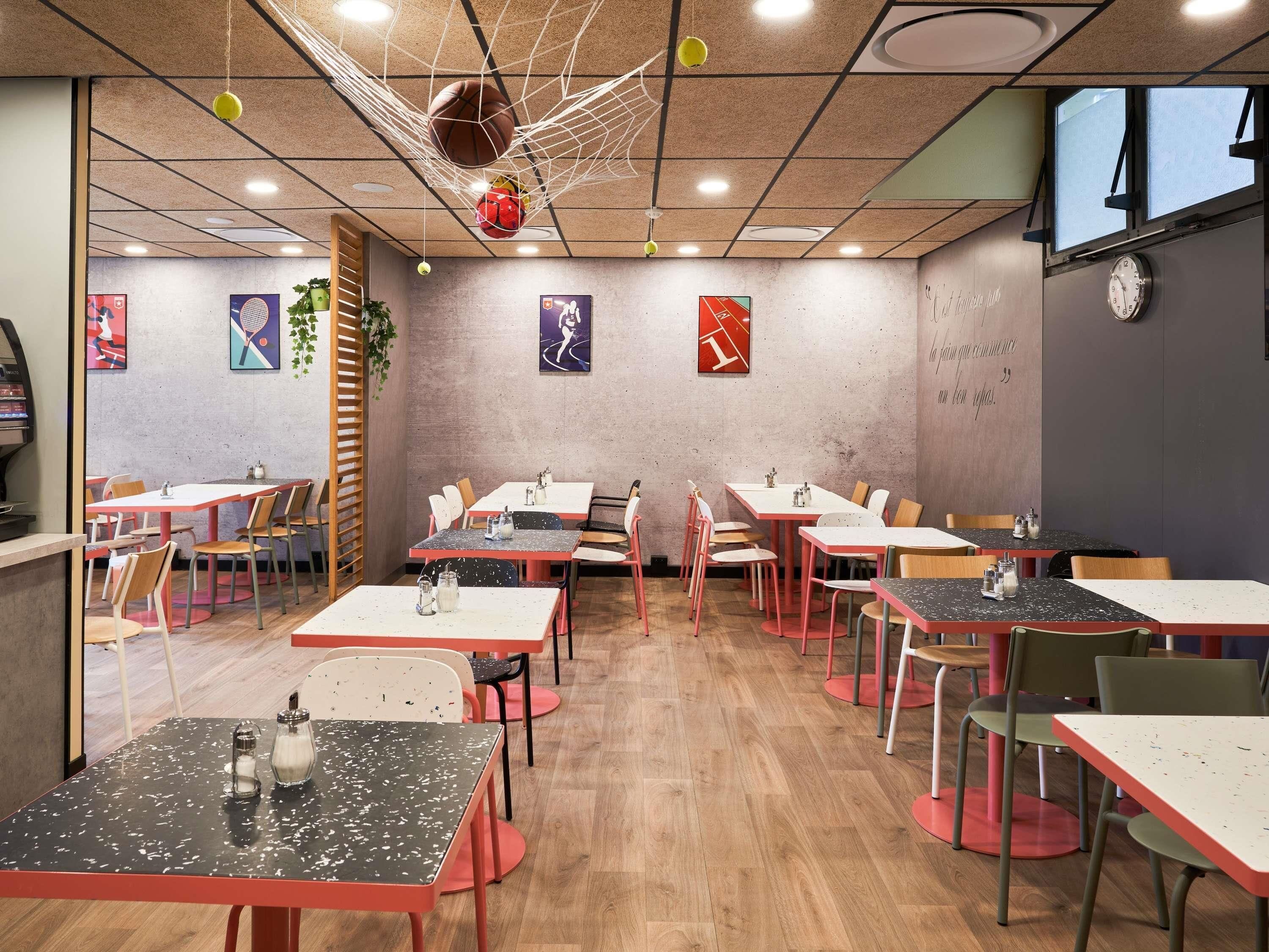 Un restaurant avec plusieurs tables et chaises, un panier de basket et des œuvres d’art murales.