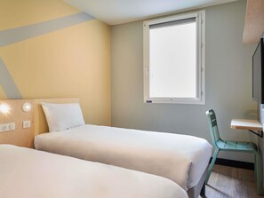 Habitación de hotel con dos camas, un escritorio, una silla, una ventana y un televisor.