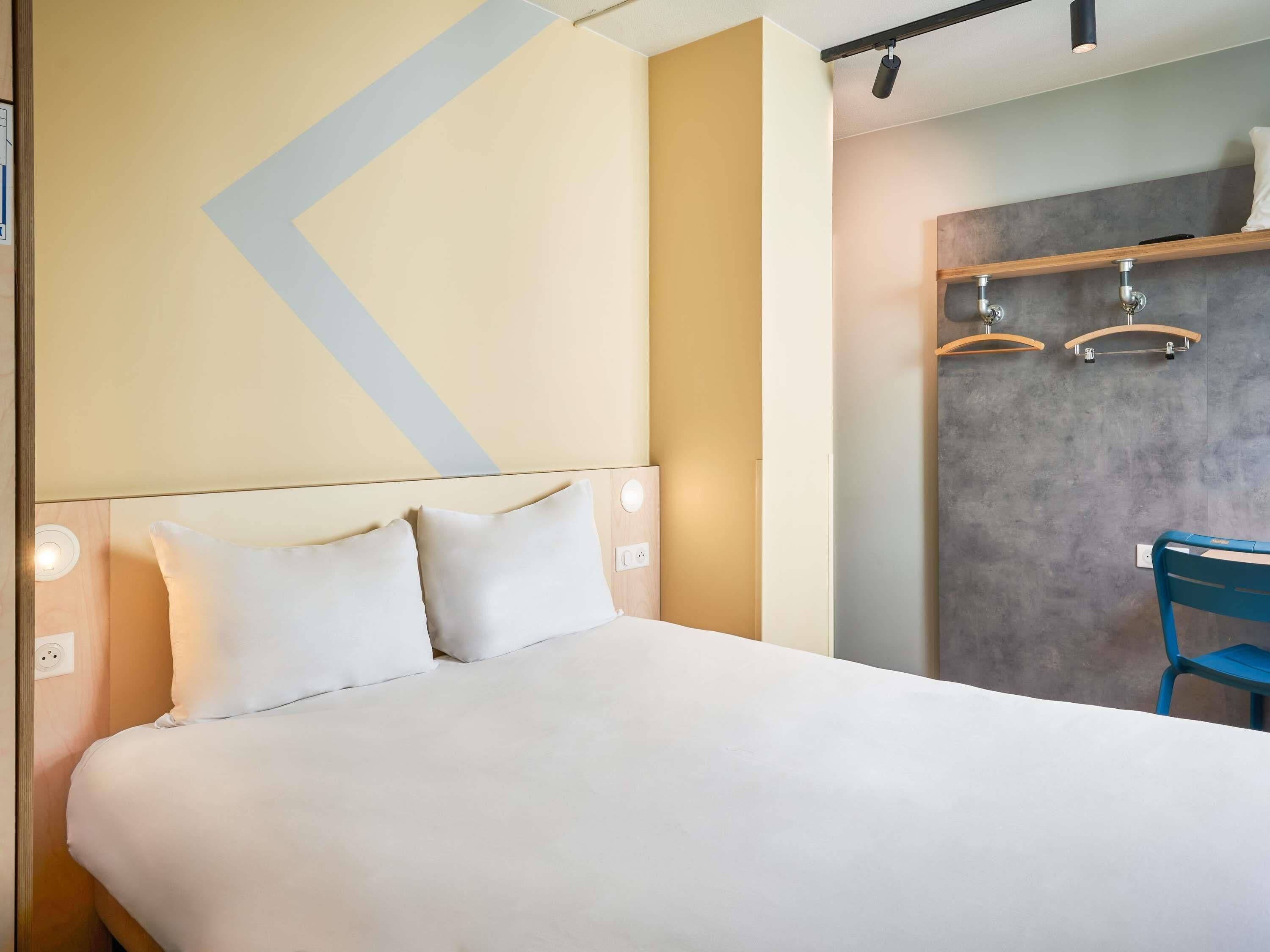 A hotel room with a bed, a desk, and a chair.