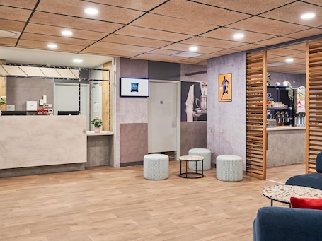 Ein Empfangsbereich mit Theke, Sitzgelegenheiten und einer Kaffeestation.. ibis budget Saint Maurice