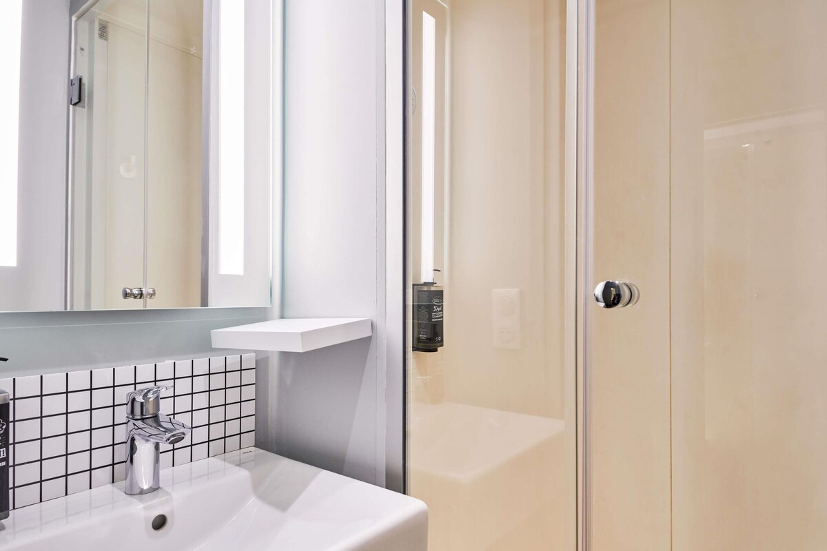 A bathroom with a white sink, a mirror, and a glass shower enclosure.