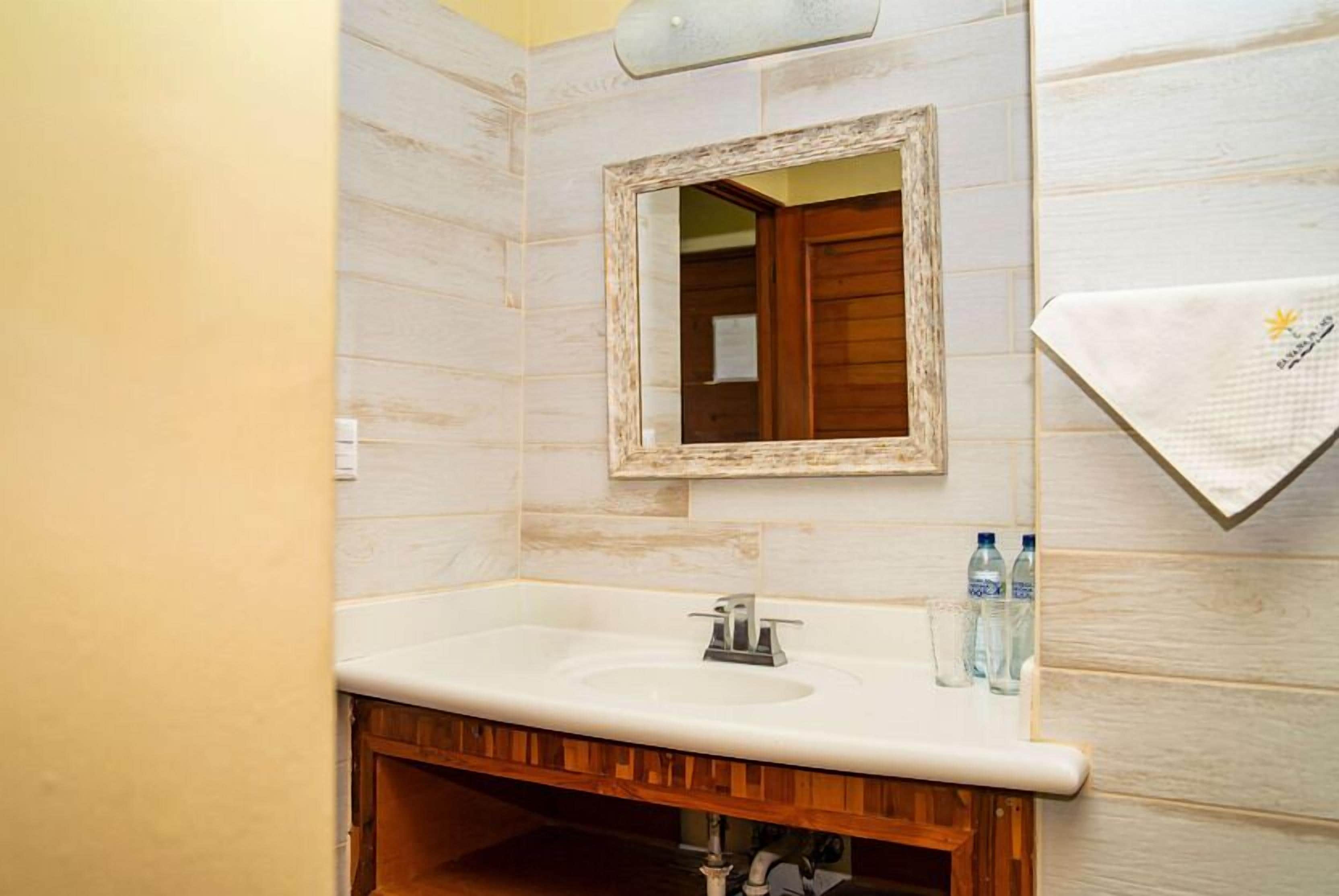 Un baño con tocador de madera, un espejo y un perchero para toallas.