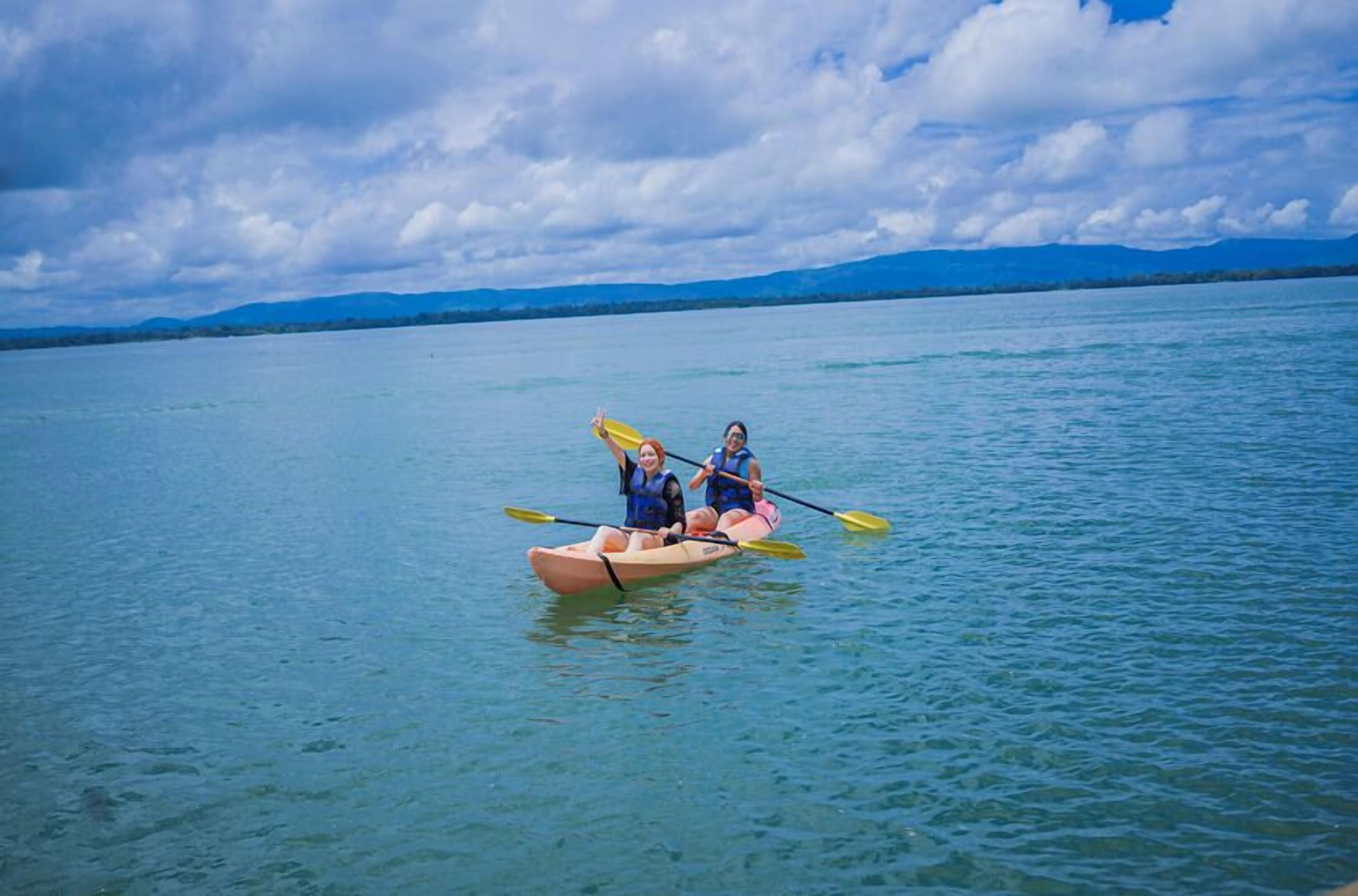 Una persona rema en kayak sobre aguas tranquilas.