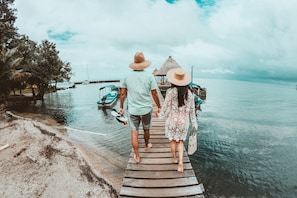 A wooden pier leading to a boat dock with a couple walking towards it.