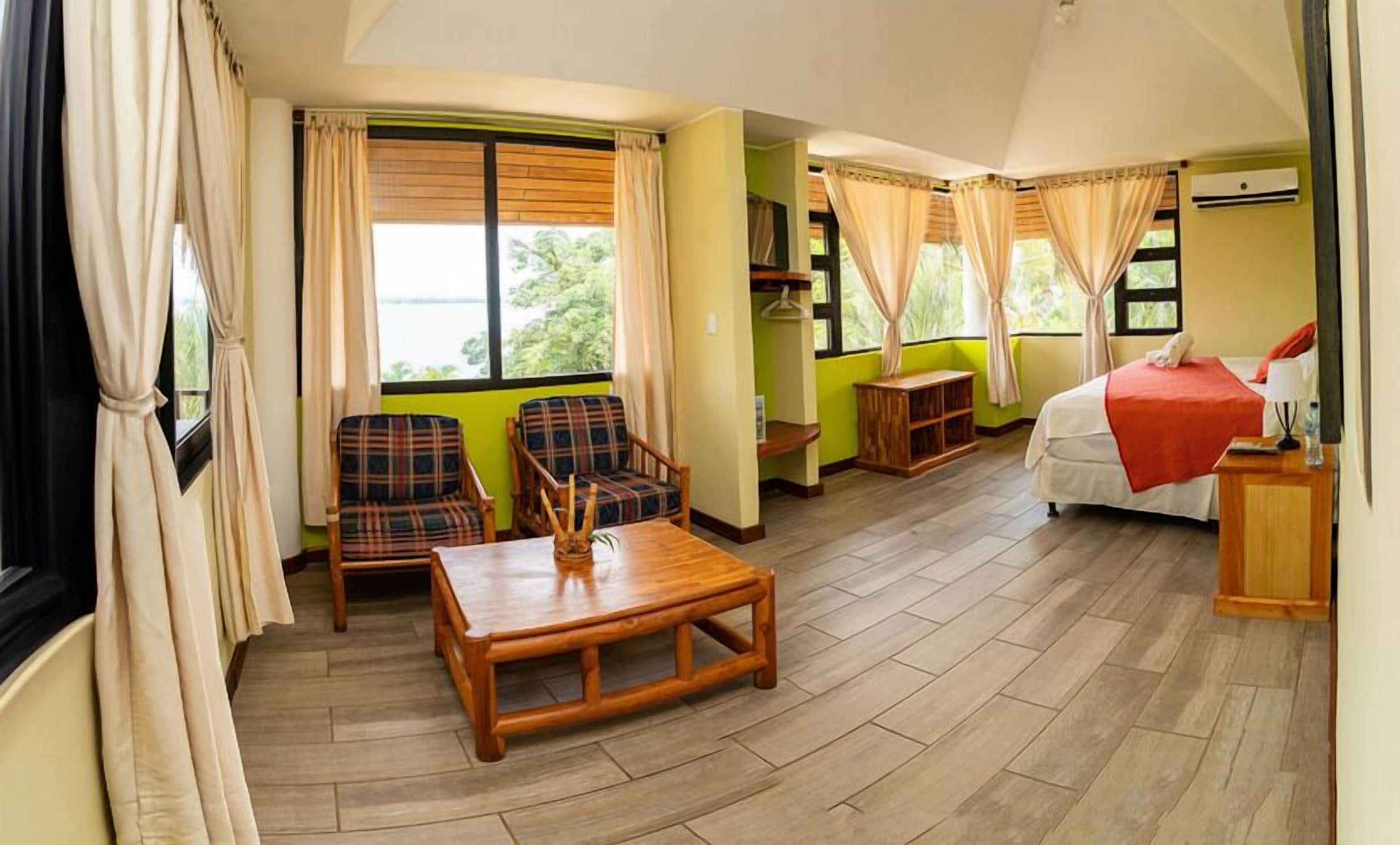 A room with a bed, two chairs, a table, and a window with curtains.