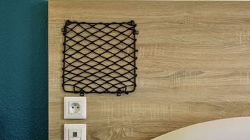 A wooden wall with a black netted object and two white electrical outlets.