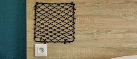 Eine Holzwand mit einem schwarzen Netz und zwei weißen Steckdosen.