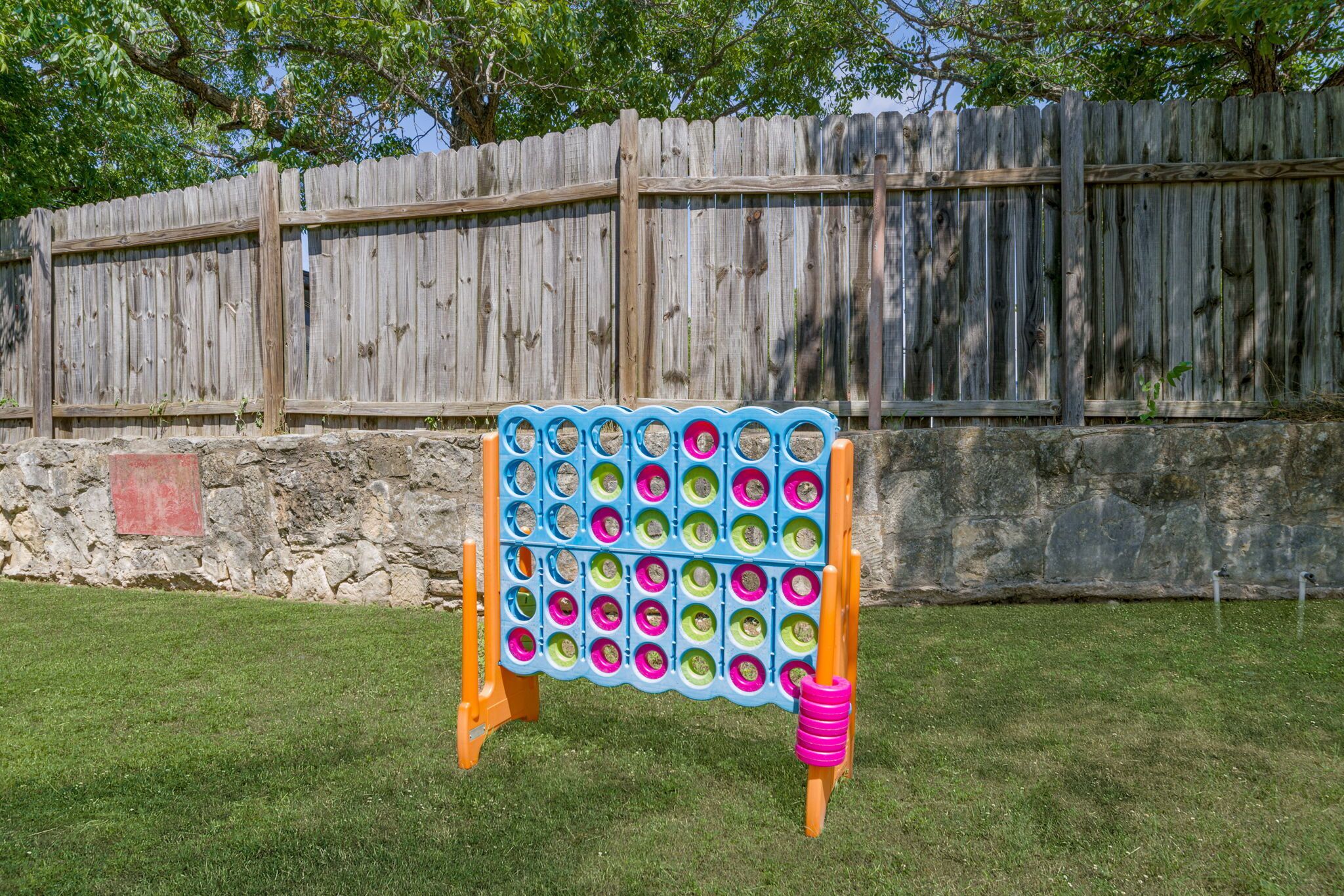 A colorful board game set up on a grassy lawn with a wooden fence in the background.