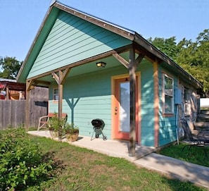 A small, single-story house with a porch, a door, and a window. - Blanco Riverside Cottages & RV (Blanco)