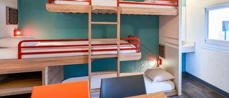 A bunk bed room with a wooden table and chairs, a window, and a wall-mounted shelf.