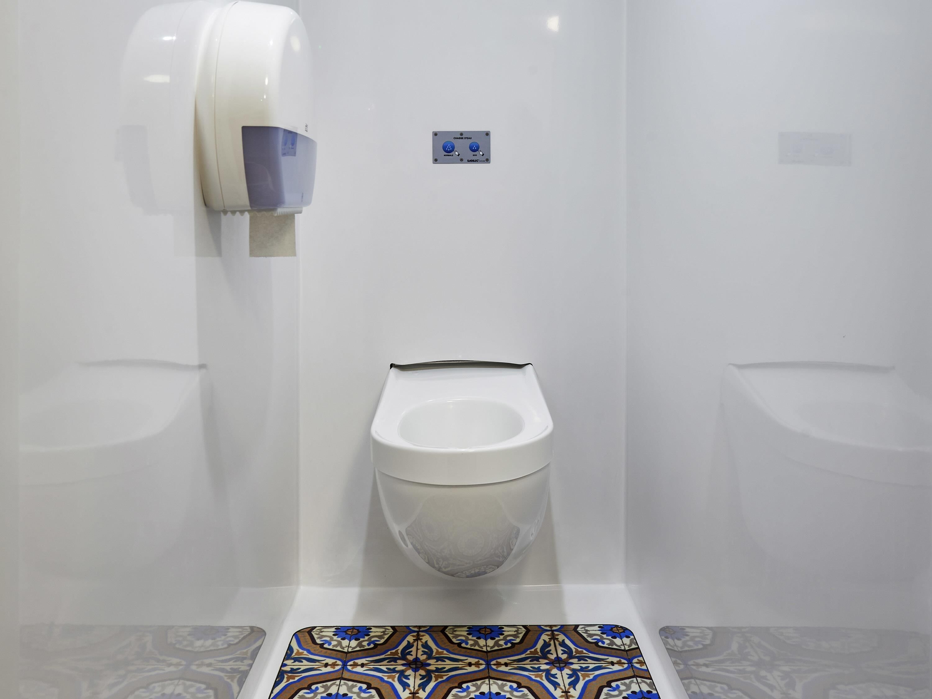 Une salle de bain moderne équipée de toilettes, d’un urinoir et d’un sèche-mains.