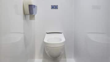Une salle de bain moderne équipée de toilettes, d’un urinoir et d’un sèche-mains.