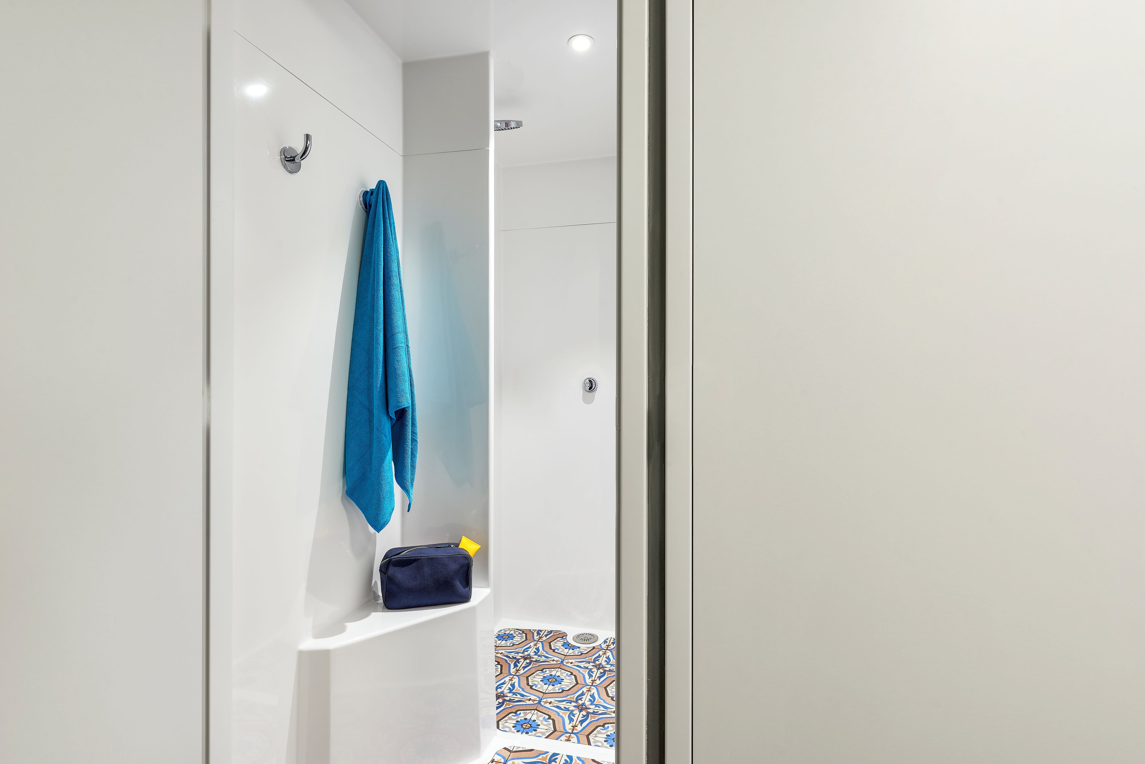 Un baño moderno con ducha, perchero y un estante pequeño.