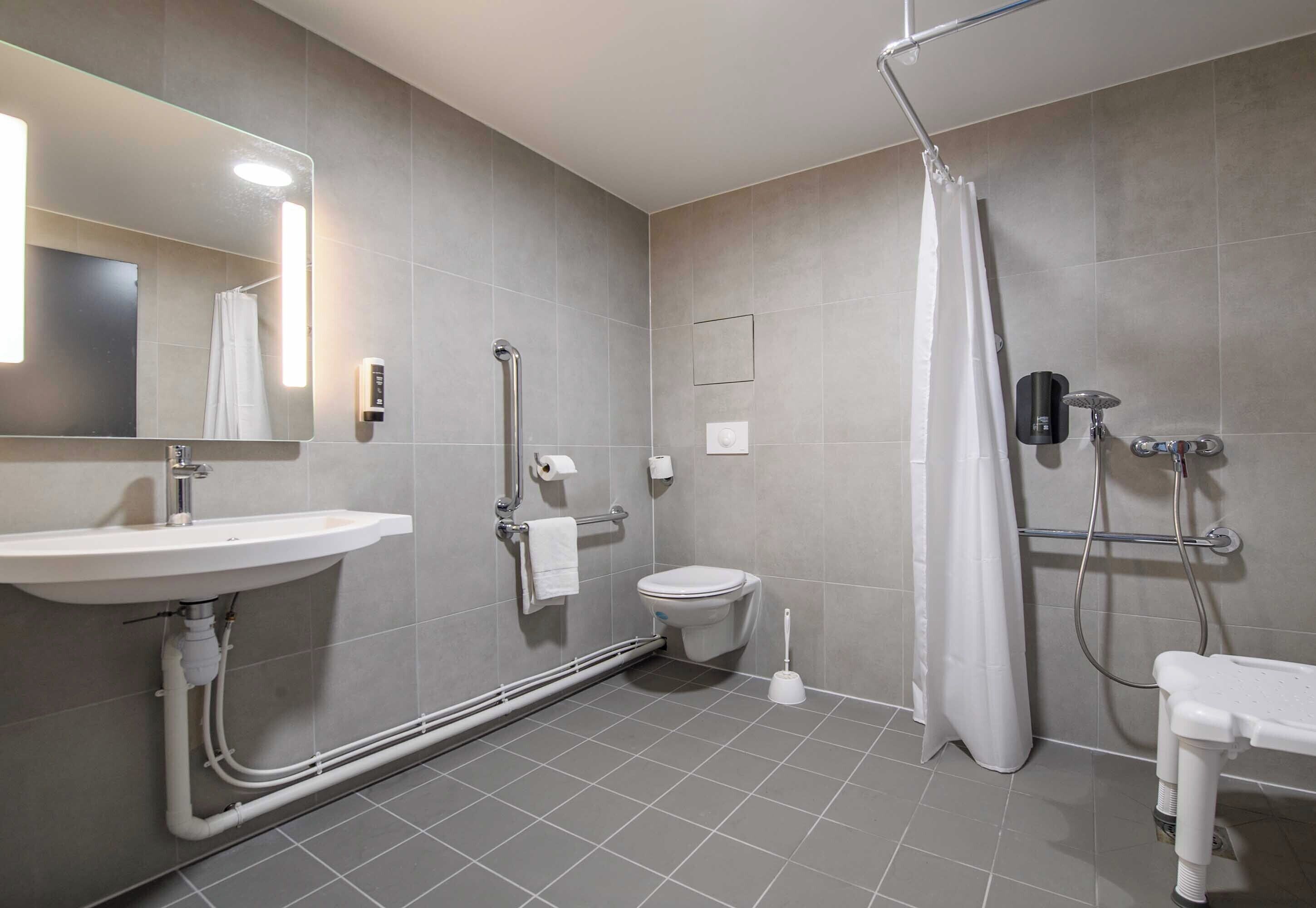 A modern bathroom with a sink, toilet, shower, and a mirror.