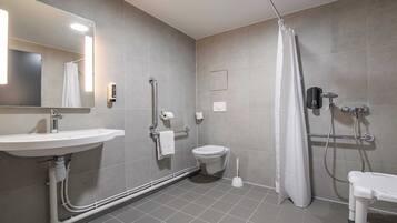 A modern bathroom with a sink, toilet, shower, and a mirror.