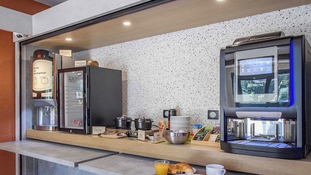 A modern breakfast bar with a coffee machine, a refrigerator, and a coffee station.