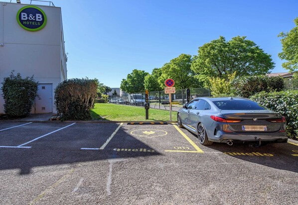 A parking area with a B&B hotel sign, a no parking sign, and a car parked in a designated space.