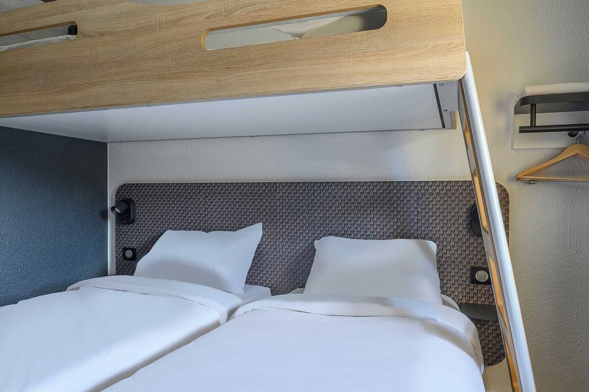 A neatly made bed with white linens and a headboard with a textured pattern.