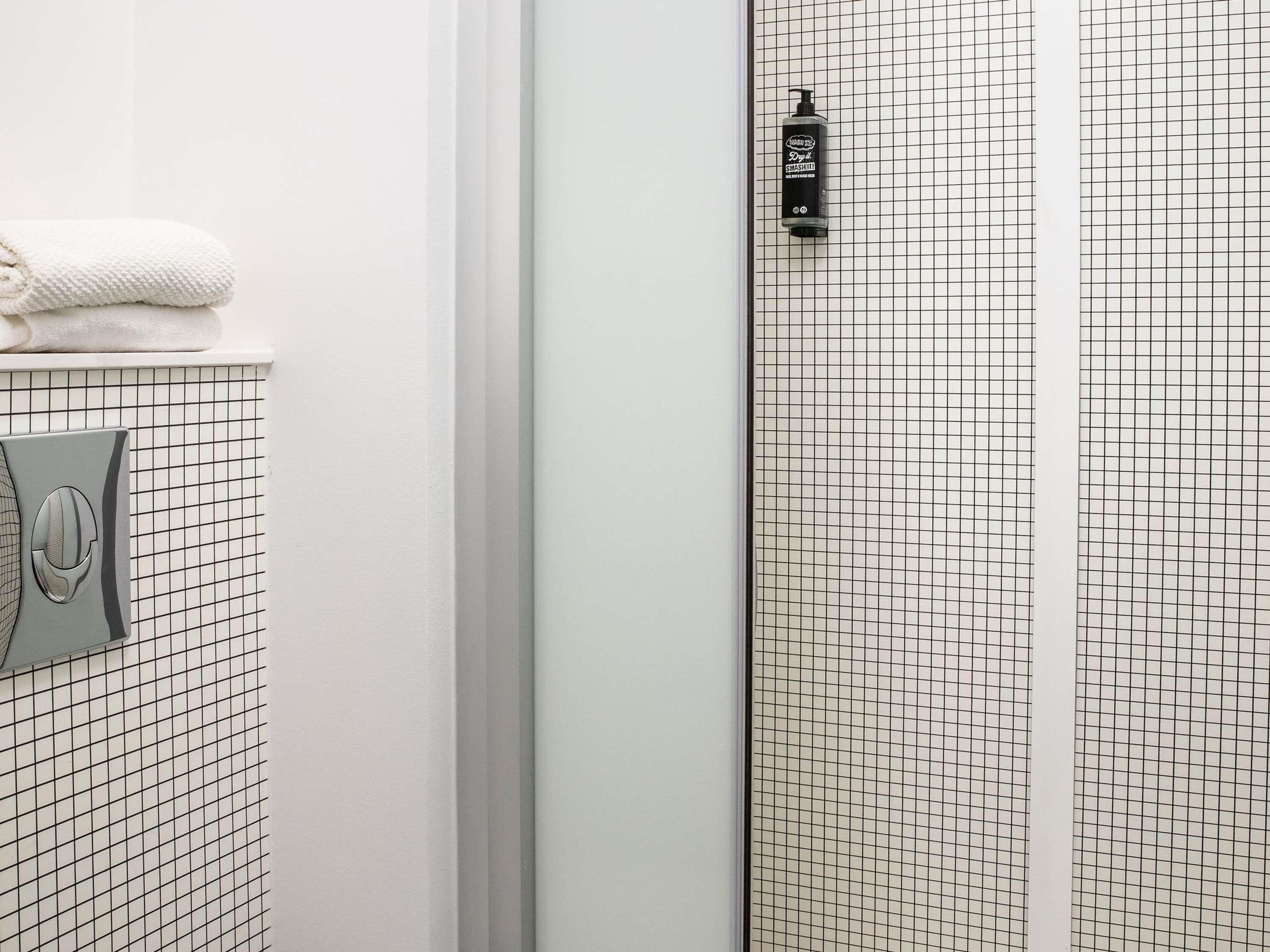 Ein Badezimmer mit gefliesten Wänden, einem Handtuch auf einer Ablage und einer Seifenspender.