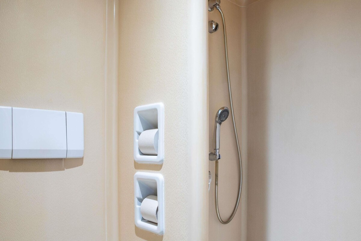 Ein Badezimmer mit Dusche, Toilettenpapierablage und Handtuchhalter.