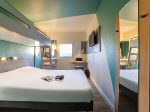 A hotel room with a bed, a desk, a chair, a window, and a mirror. - ibis budget Sucy en Brie (Sucy-en-Brie)