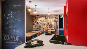 Un intérieur moderne avec un mur noir ardoise, des tables en bois et un mur d’accent rouge.