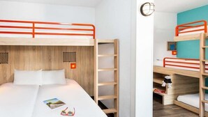 Een kamer met stapelbedden, een houten ladder, een wit bed en een klein plankje met een teddybeer.