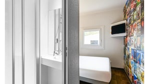 Een slaapkamer met een bed, een aan de muur bevestigde televisie en een raam.