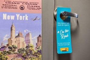 A door with a blue hotel tag that reads 'On the Road' and 'NE PAS DÉRANGER DO NOT DISTURB'.