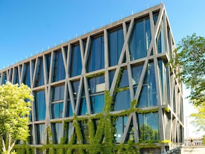 Een modern gebouw met een rastergevel, grote ramen en beplanting op de buitenkant.