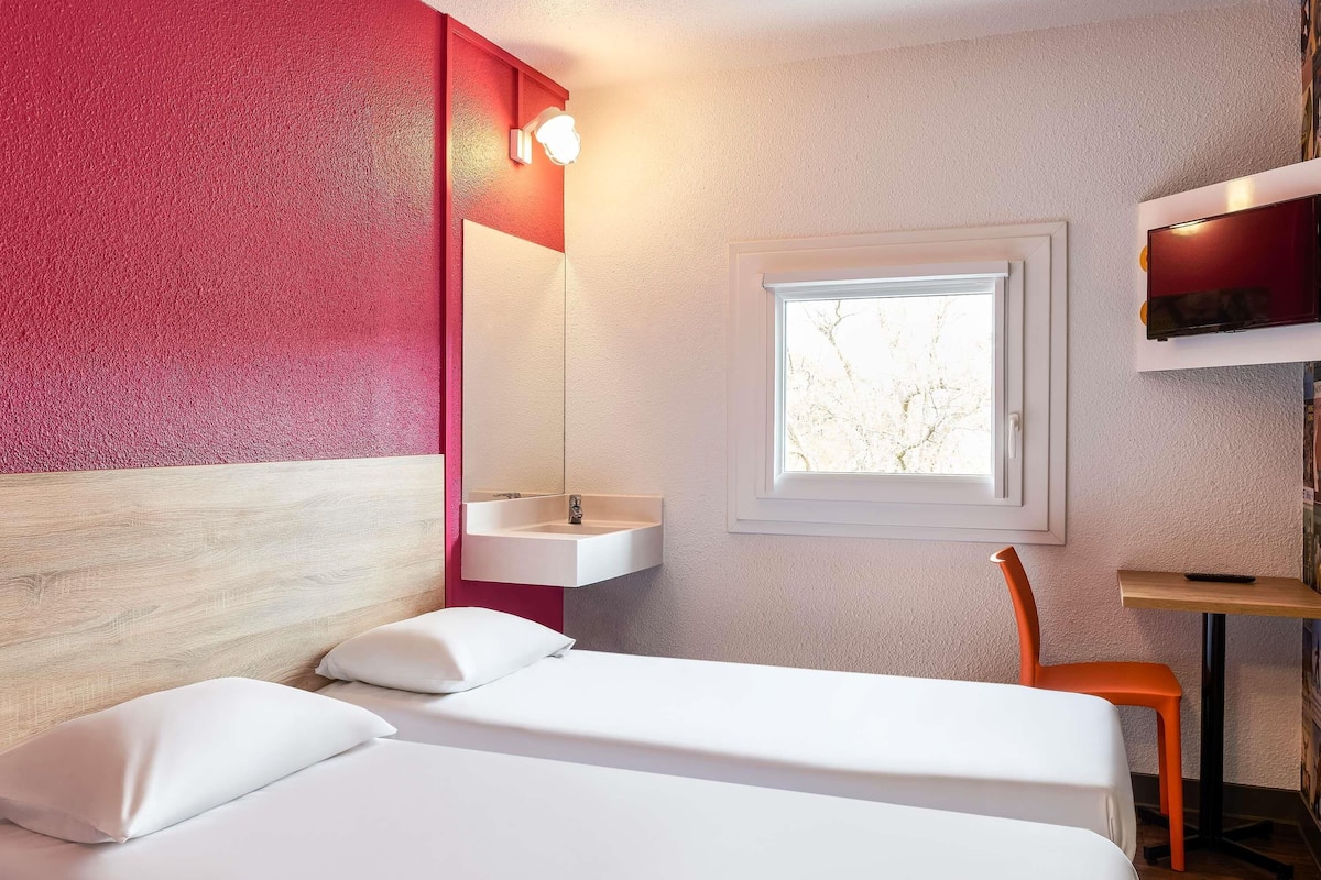 Une pièce avec un lit, une fenêtre, un lavabo et une chaise.
