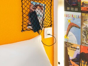 Eine Wand mit gelber Struktur, eine weiße Steckdose und ein schwarzes Kabel, das mit einem Telefon verbunden ist.