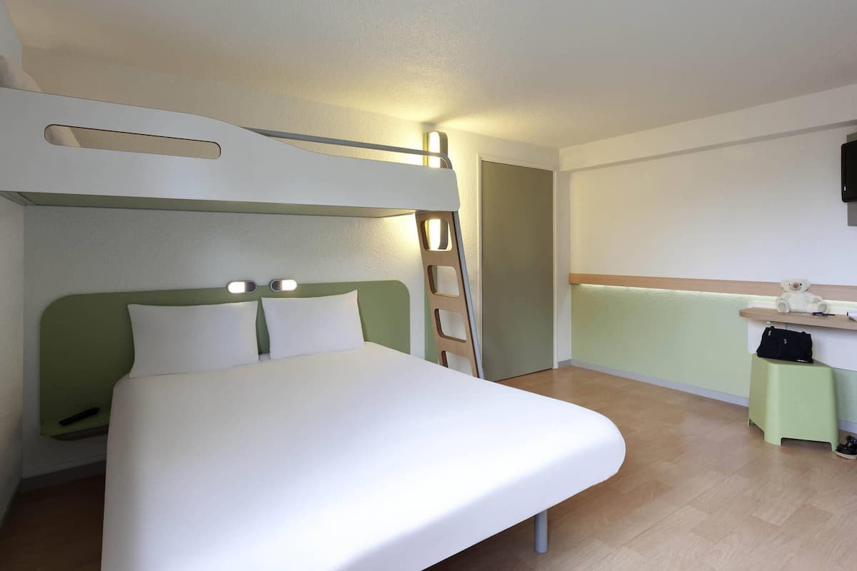 A room with a bed, a desk, a chair, and a television.