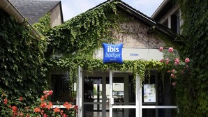 A hotel entrance with a sign for 'ibis budget hotels' and a name 'Tarbes'. - ibis budget Tarbes (Tarbes)