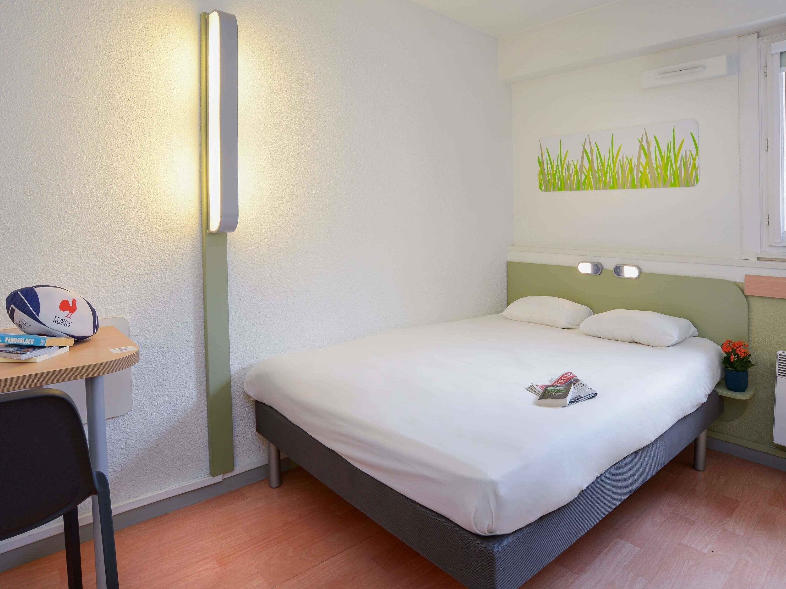 A neatly arranged hotel room with a bed, a desk, and a chair.