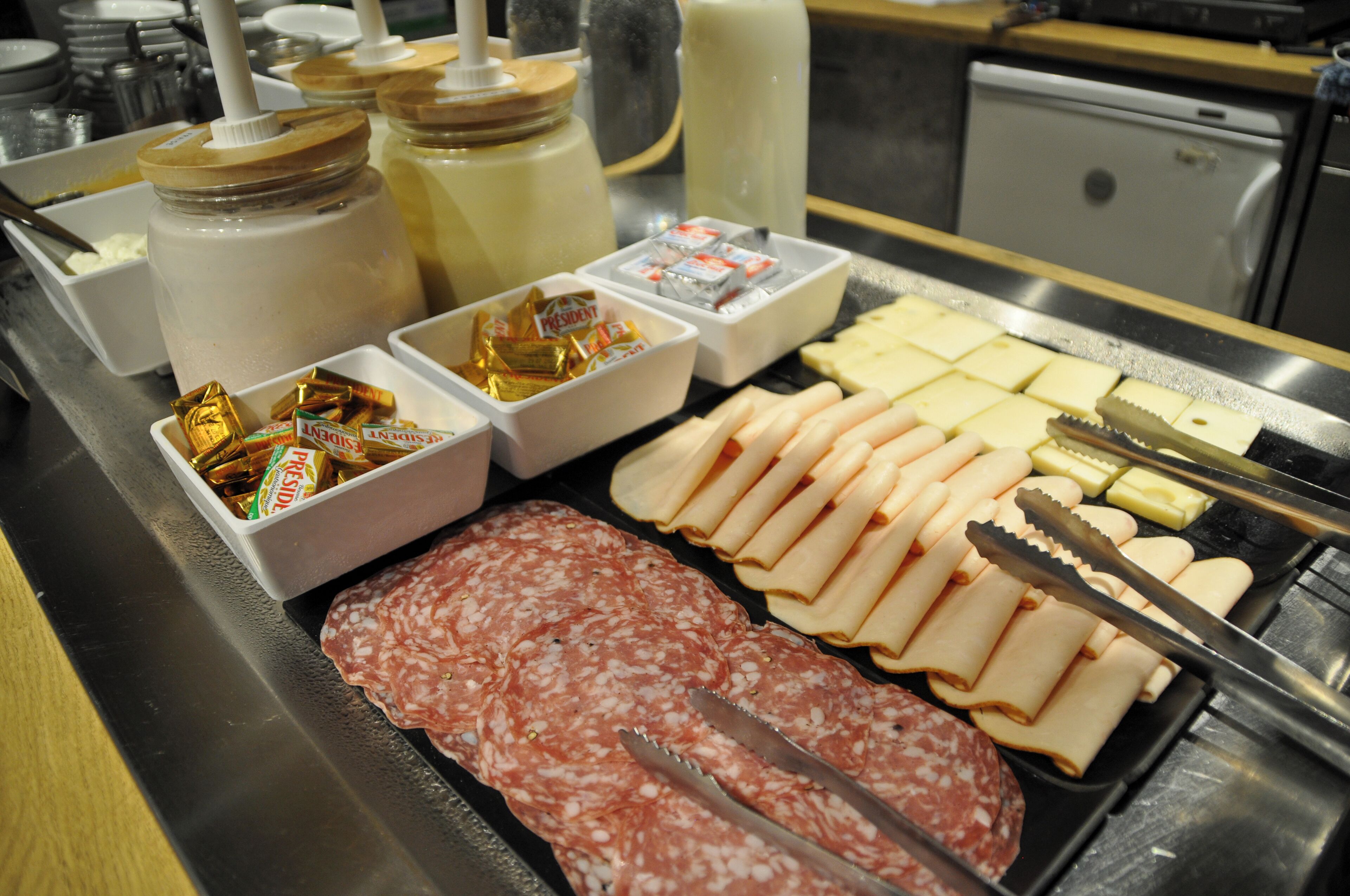 A buffet with various food items including sliced meats, cheeses, and condiments.