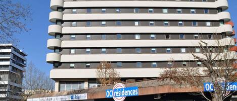 Un hotel de varios pisos con diseño moderno, con balcones en cada planta y un cartel con la leyenda 'ibis budget' en la parte superior.
