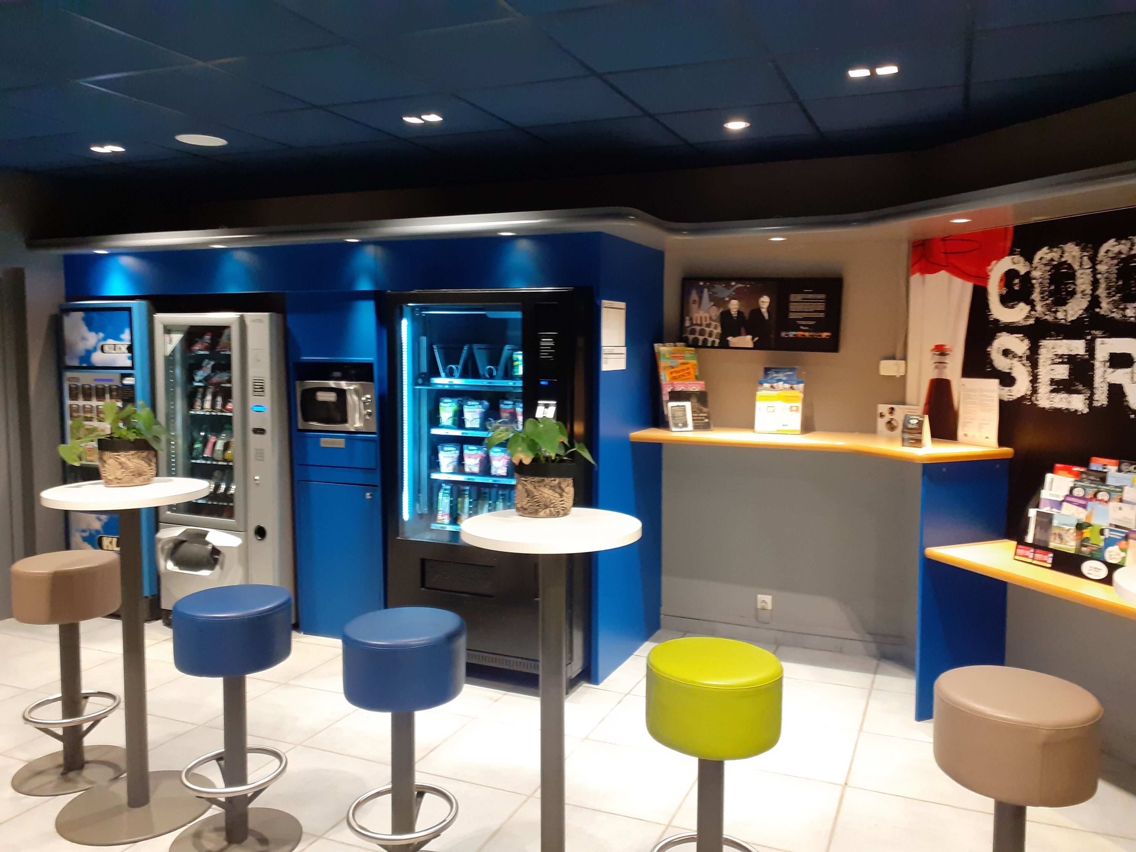 A modern bar area with blue walls, a vending machine, and stools.