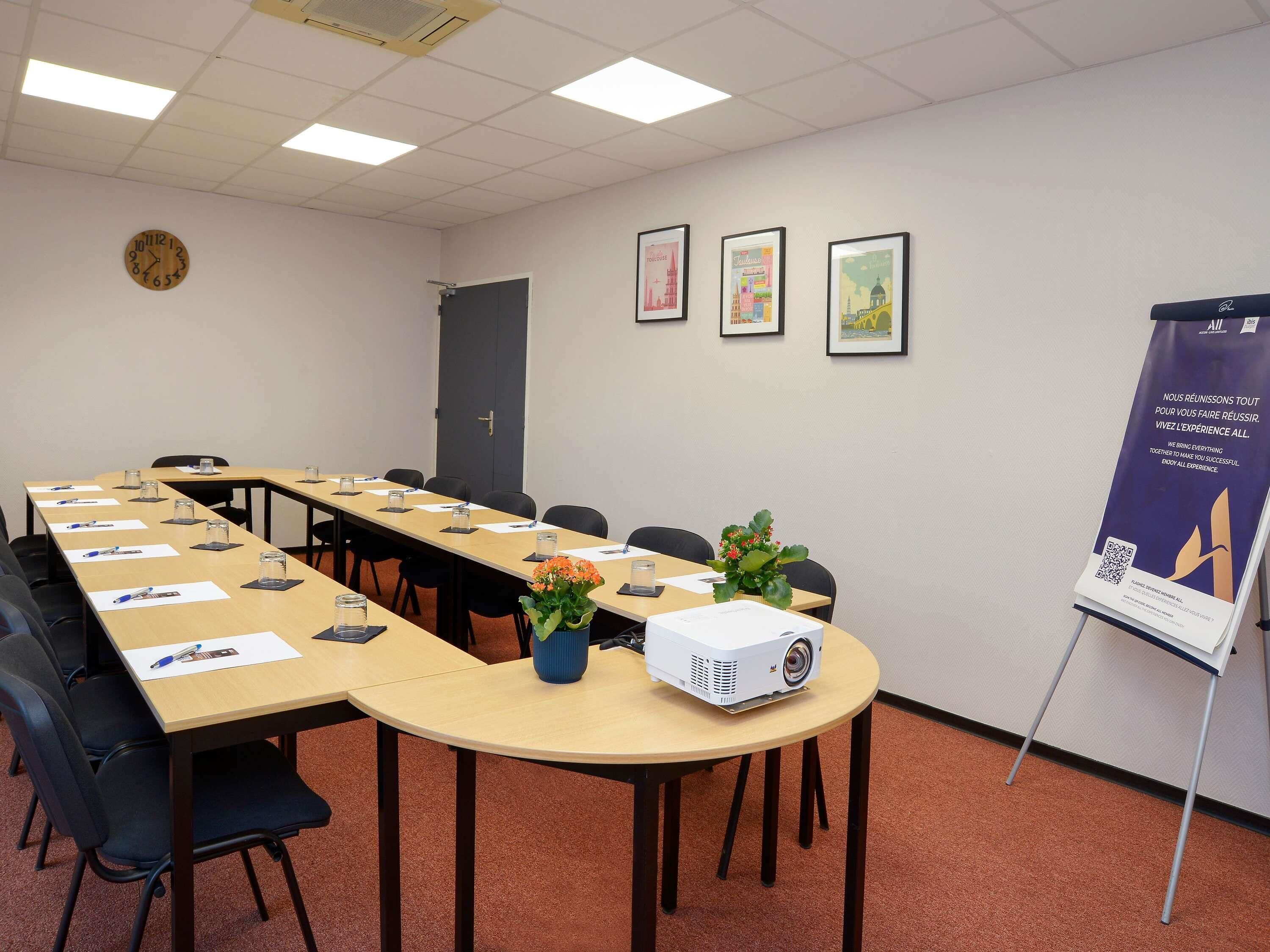 Une salle de conférence avec une longue table, des chaises, un projecteur et une affiche accrochée au mur.