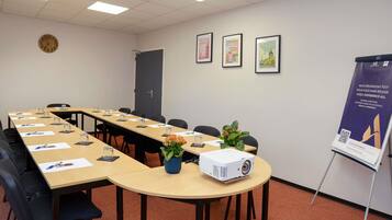 Une salle de conférence avec une longue table, des chaises, un projecteur et une affiche accrochée au mur.