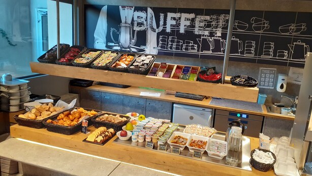 A buffet counter with various food items, including pastries, fruits, and condiments. - ibis budget Toulouse Centre Gare (Toulouse)