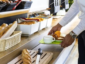 A buffet setup with bread, croissants, and a coffee cup on a tray. - ibis budget Paris Porte de Bercy (Charenton-le-Pont)