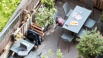 Un patio al aire libre con varias mesas y sillas, rodeado de cercas de madera y plantas en macetas.