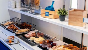 Un bufé con diversas opciones de comida, como pan, pasteles y salsas.