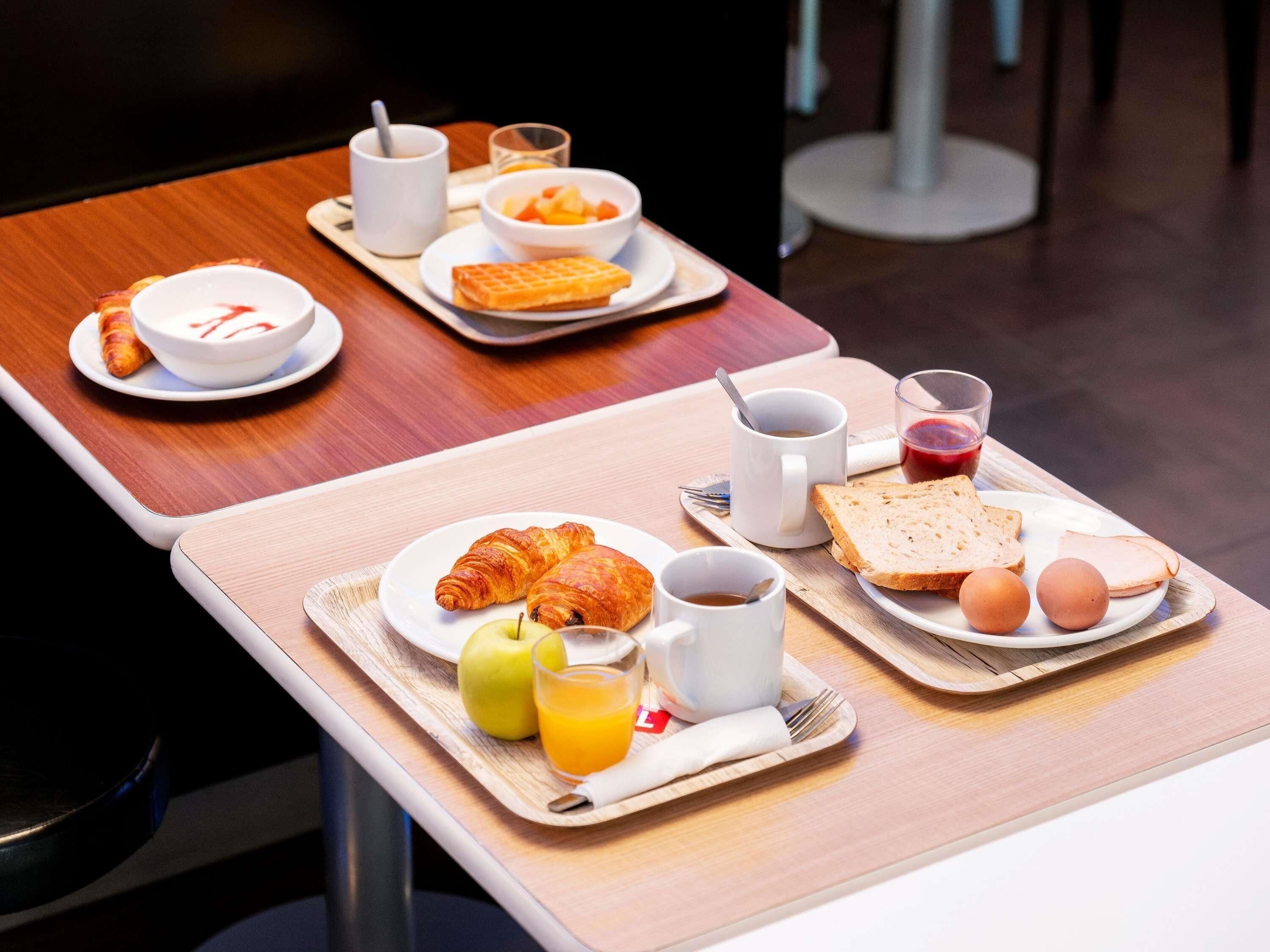 Bandeja de desayuno con cruasanes, manzanas, zumo de naranja y tostadas con huevos.